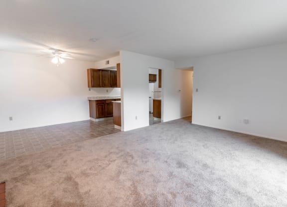 an empty living room and kitchen with white walls and carpet