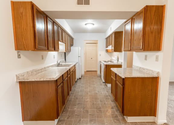 a kitchen with wooden cabinets and marble counter tops