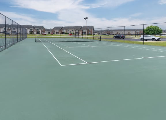 a green tennis court with white lines on a fence