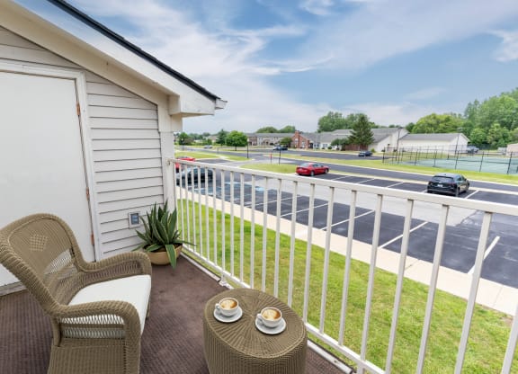 a balcony with two chairs and a table overlooking a parking lot