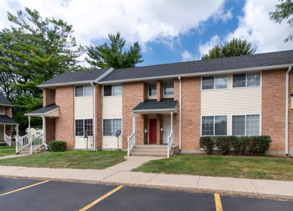 an apartment building with brick and white siding and a lawn