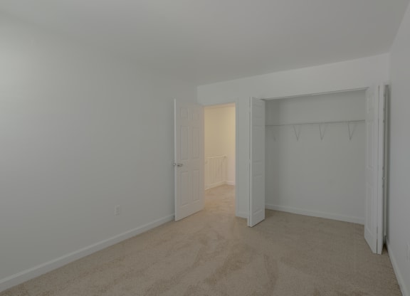 a bedroom with white walls and carpet and a closet