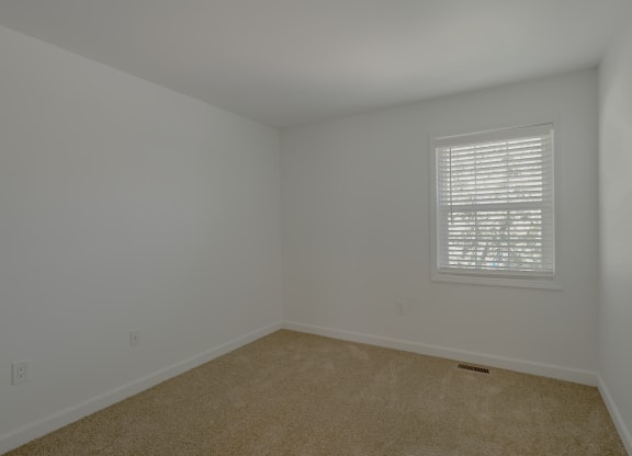 an empty room with white walls and a window