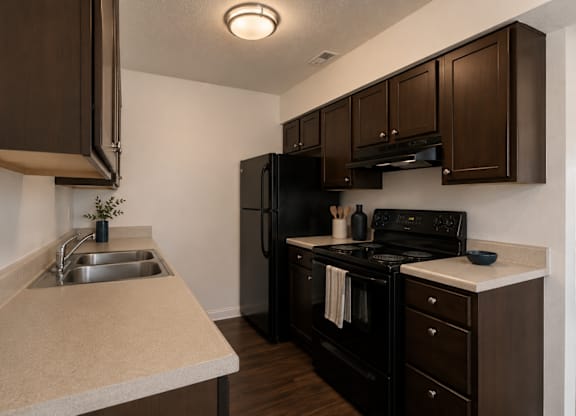 A kitchen with brown cabinets and black appliances.