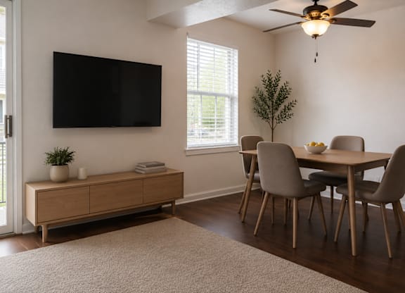 A living room with a television, a table with chairs, and a potted plant.