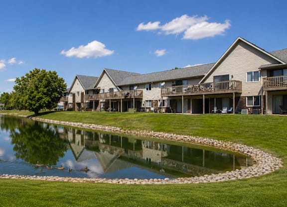 A lake in front of a building with a clear blue sky.