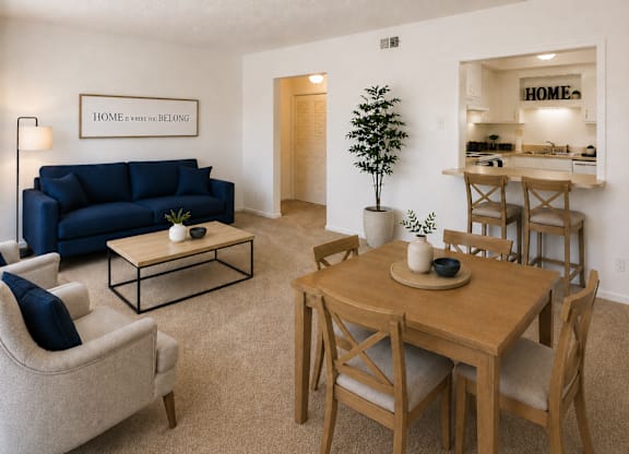 A living room with a blue couch and a wooden dining table.