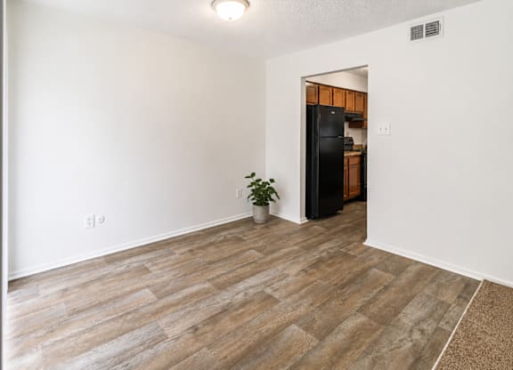 A room with a wooden floor and a black refrigerator.