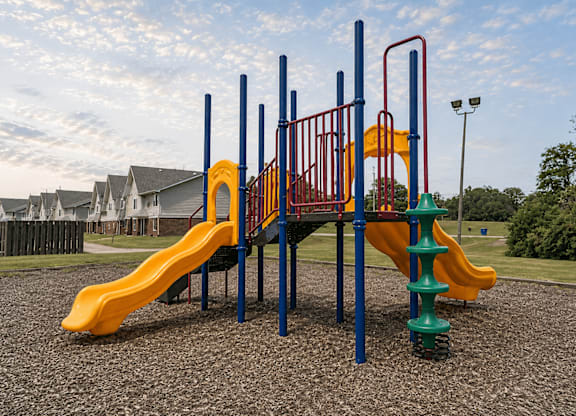 A playground with a yellow slide and a red and blue structure.