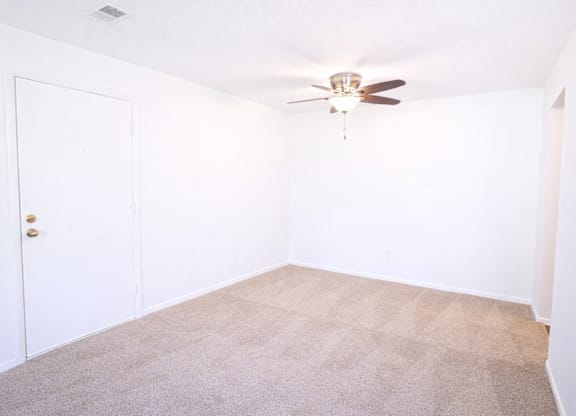 A room with a ceiling fan and carpeted floor.