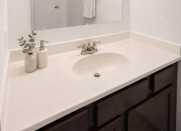 A bathroom with a white sink and a mirror with lights above it.