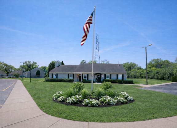 A flag is flying in front of a building with a grey roof.