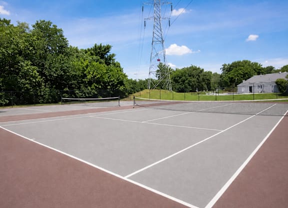 A tennis court with a net and a tall tower in the background.
