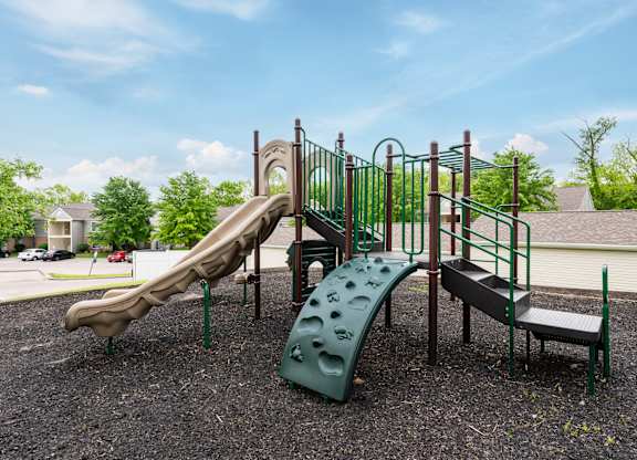 A playground with a green slide and a brown slide.