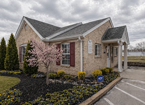 A small brick house with a red door and a sign that says "ADT" in front of it.
