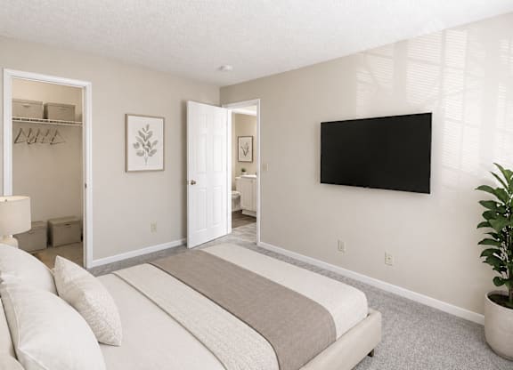 A bedroom with a large bed and a flat screen TV mounted on the wall.