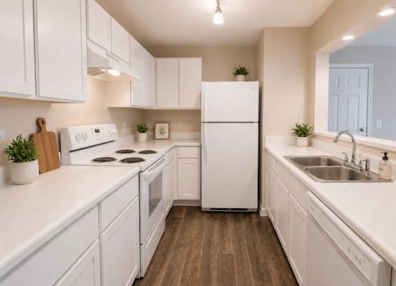 A white kitchen with a white fridge and white cabinets.