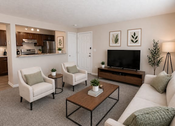 A living room with a white couch, two chairs, a coffee table, and a television.