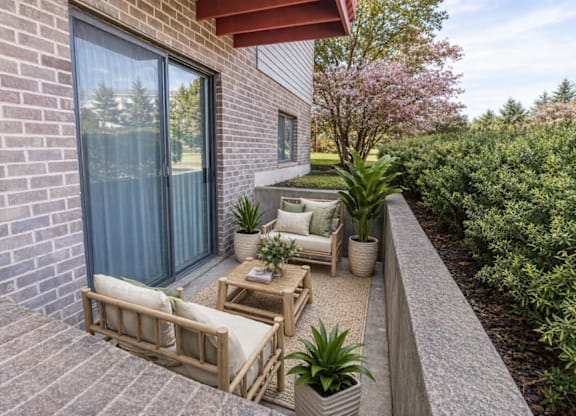 A patio with a couch, table, and potted plants.