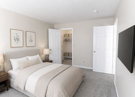 A bedroom with a large bed and a flat screen TV mounted on the wall.