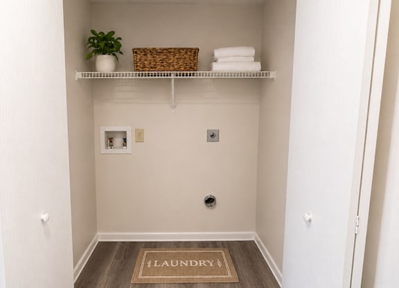 A small laundry room with a basket and towels on the shelf.