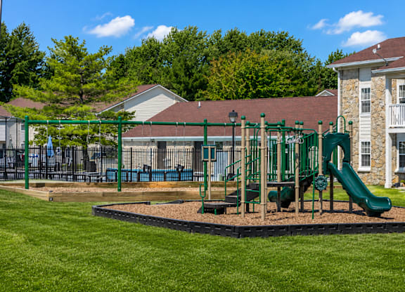 A playground with a green slide and a green fence.
