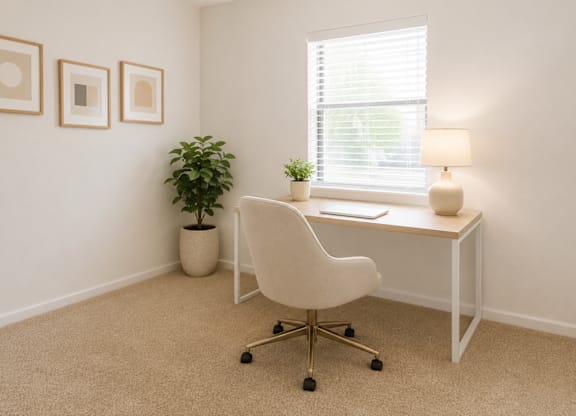 A white chair is in front of a desk with a lamp and a plant.