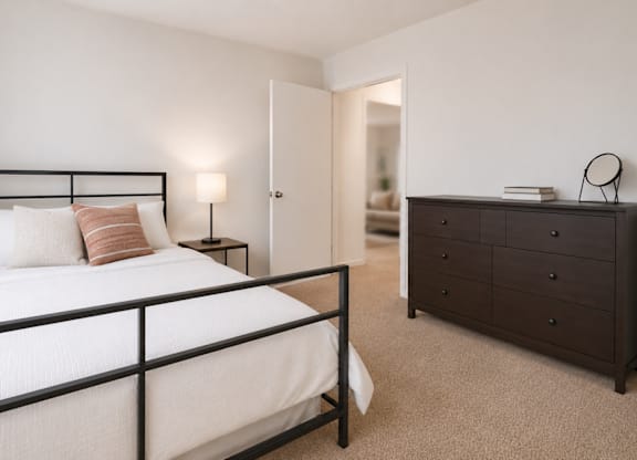 A bedroom with a bed, nightstand, and dresser.
