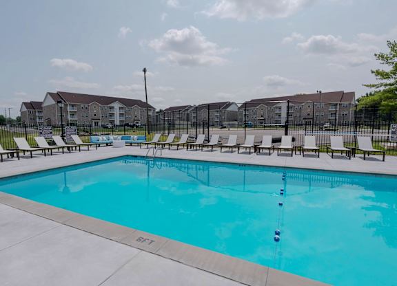 A large swimming pool with lounge chairs and a building in the background.