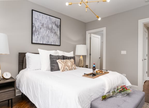 a bedroom with a white bed and a table with a bottle of wine