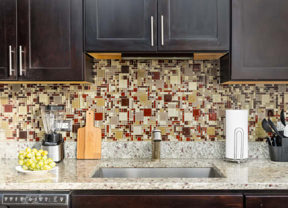 a kitchen counter with a sink and a tile backsplash