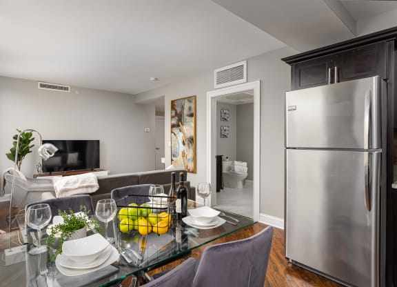 a kitchen and living room with a glass table and a refrigerator