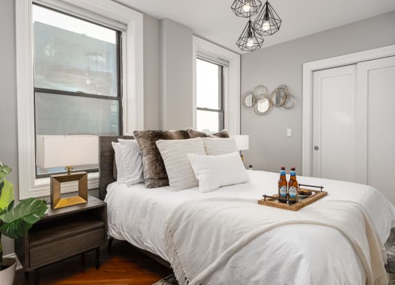 a bedroom with a white bed and two windows