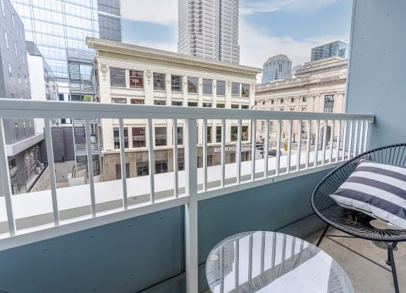 a balcony with two chairs and a table and a view of the city