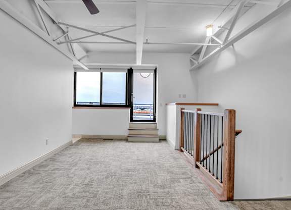 A spacious room with a large window and a ceiling fan at 100 South Apartments, Buffalo