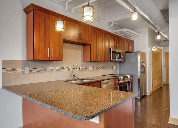 Kitchen with island granite countertops and pendant lighting at 100 South Apartments, New York, 14202