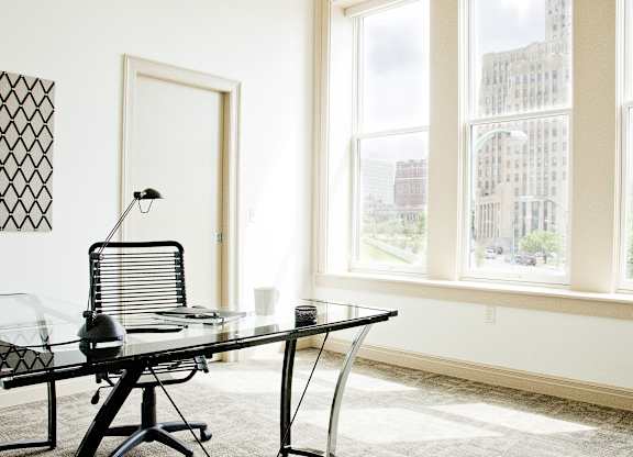 a glass desk in a room with three windows at 100 South Apartments, Buffalo, NY 14202