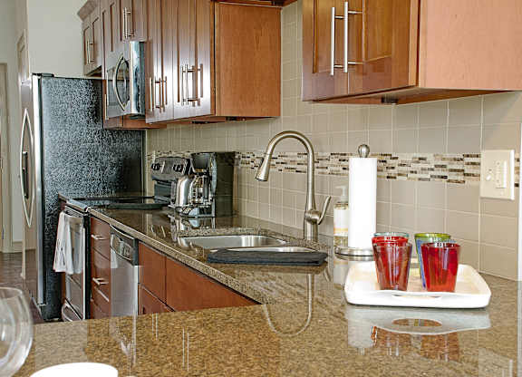 a kitchen with a sink and a counter with drinks on a tray at 100 South Apartments, Buffalo, NY