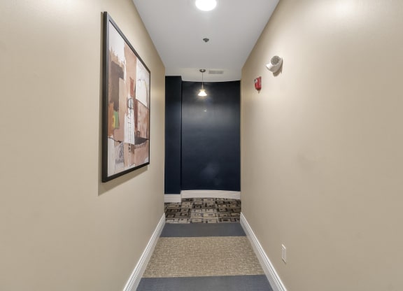 a long hallway with a black accent wall and carpeted flooring and a staircase at The Granite Works Apartments , Buffalo, New York
