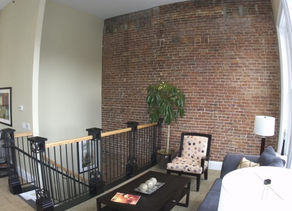 a living room with a brick wall and a couch and a chair at The Granite Works Apartments , New York 14202