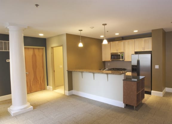 an empty kitchen and living room with a counter and refrigerator at The Granite Works Apartments , Buffalo, NY