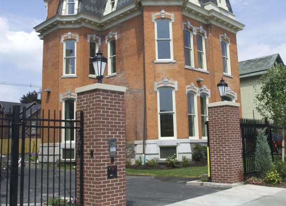 a red brick house with a black wrought iron gate at The Granite Works Apartments , Buffalo