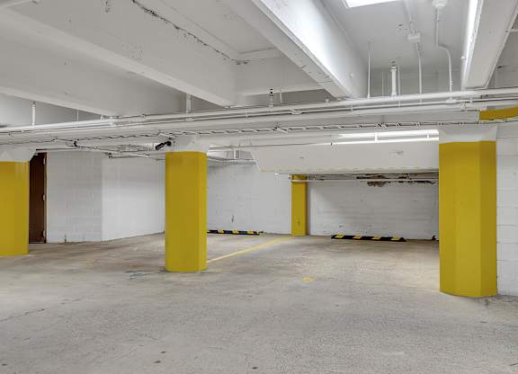 a parking garage with white walls and yellow pillars at 100 South Apartments, Buffalo, New York