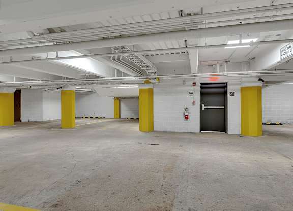 a parking garage with yellow pillars and a door at 100 South Apartments, Buffalo, 14202