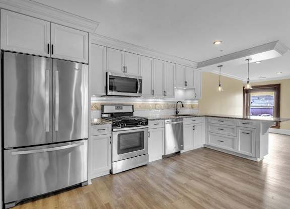 a kitchen with stainless steel appliances and white cabinets at The Knights @ 506 Delaware Apartments, New York