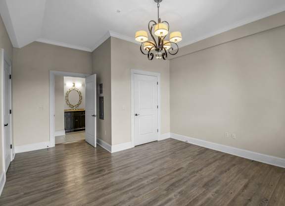 an empty living room with wood floors and a chandelier at The Knights @ 506 Delaware Apartments, Buffalo, 14202
