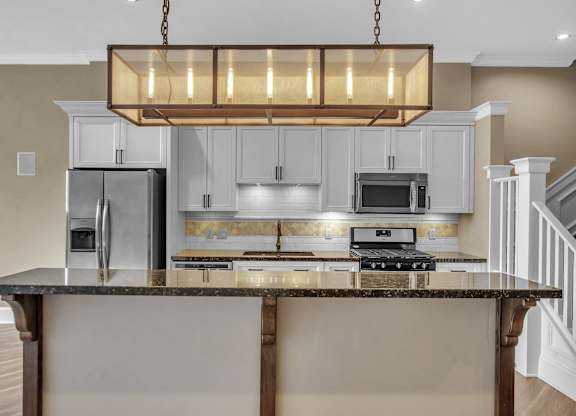 a kitchen with an island with a granite counter top and white cabinets at The Knights @ 506 Delaware Apartments, Buffalo, NY 14202