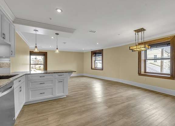 an open kitchen and living room with white cabinets and wood floors at The Knights @ 506 Delaware Apartments, New York, 14202