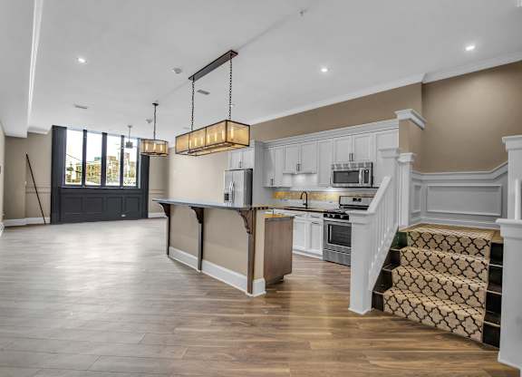 a large kitchen with white cabinets and a large island at The Knights @ 506 Delaware Apartments, New York