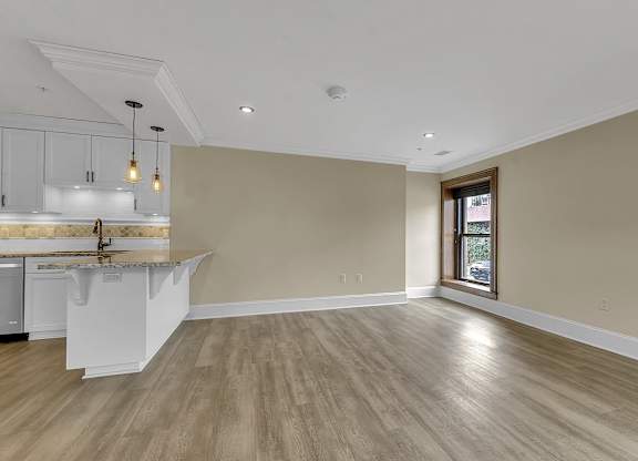 an empty living room with a kitchen and a window at The Knights @ 506 Delaware Apartments, Buffalo